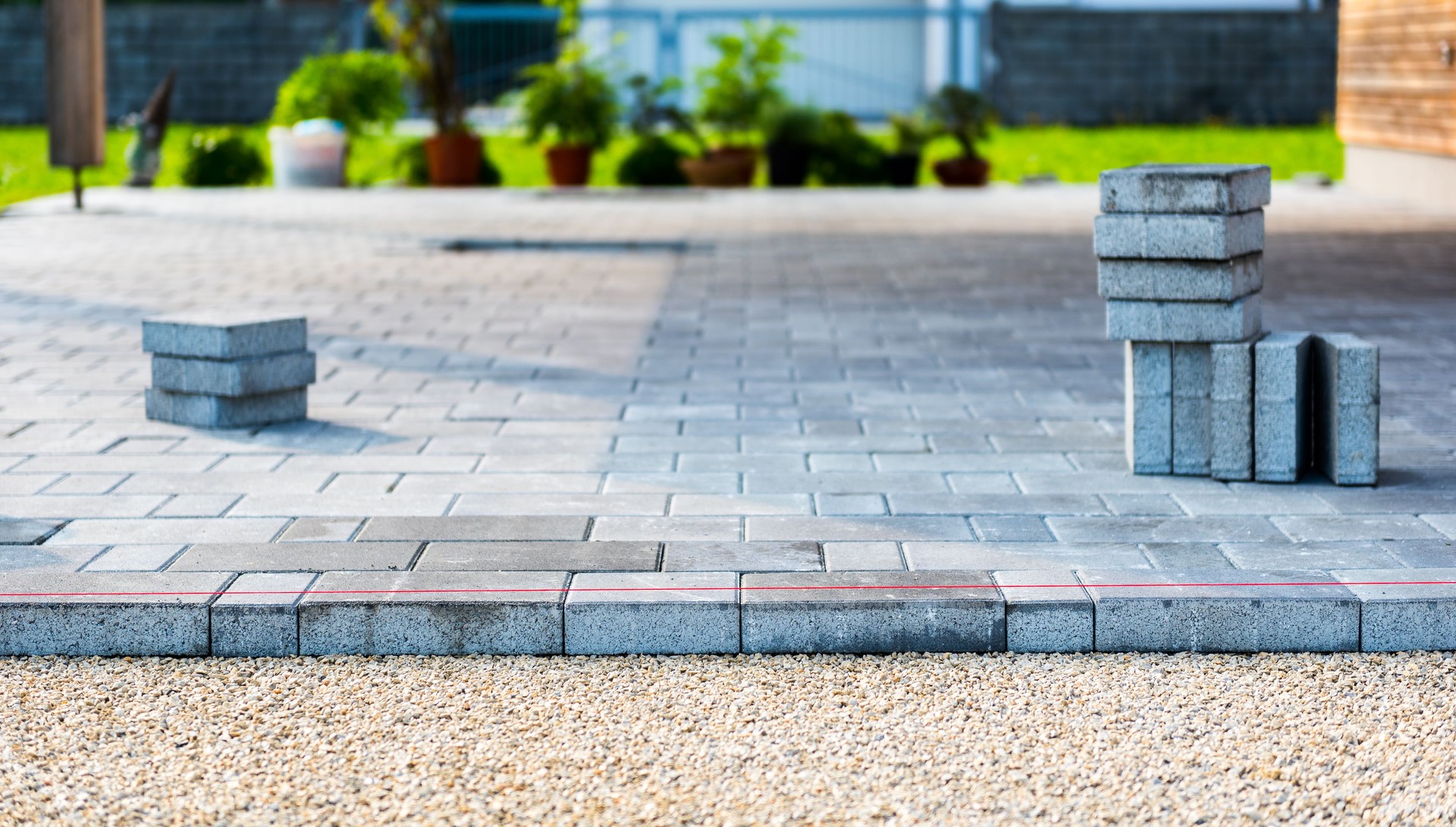 Laying gray concrete paving slabs in house courtyard driveway patio.